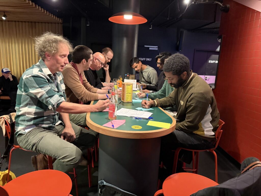 The participants of the Human Future Hub Meetup think about their answers gathered around the table. The setting is calm, colourful and gives a sense of a workshop.
